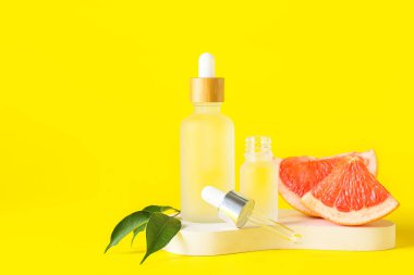 Sarı arka planda gerekli yağ ve greyfurt dilimleri.