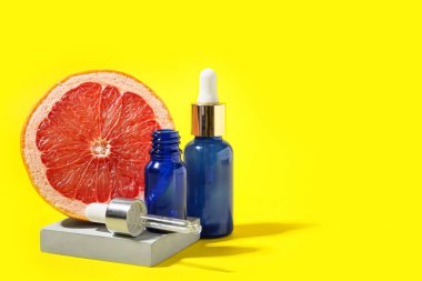 Önemli yağlı şişeler ve sarı arka planda sulu greyfurt.