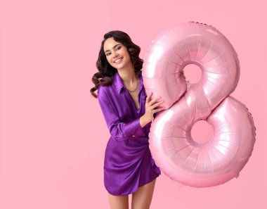 Pembe arka planda 8 şeklinde balonu olan gülümseyen genç bir kadın. Uluslararası Kadınlar Günü