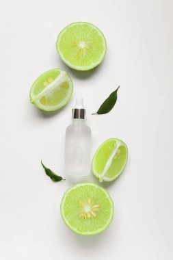 Temel yağ şişesiyle kompozisyon ve beyaz arka planda bergamot meyveleri kesme