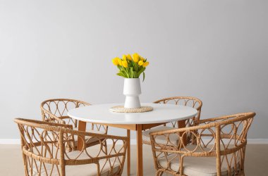 Yemek masasının yanında lale vazosu olan bir vazo.