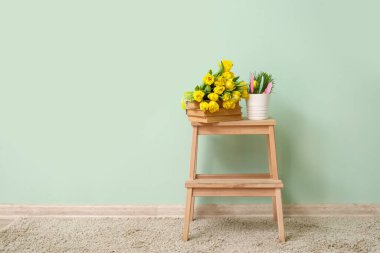 Lale buketi, kitap yığını ve odanın renk duvarının yanındaki merdivende Paskalya dekoru.