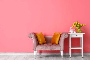 Laleli vazo, Paskalya yumurtası, masada tavşan ve odada renkli duvarın yanındaki koltuk.