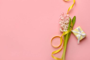 Uluslararası Kadınlar Günü kutlamaları için pembe arka planda kurdeleli, çiçekli ve hediye kutulu kompozisyon