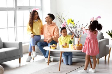 Paskalya günü aileleri evde ağaç dalları süsleyen küçük çocuklar.