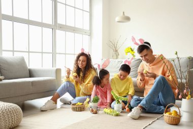 Küçük çocuklar ve aileleri evde paskalya yumurtası boyuyorlar.