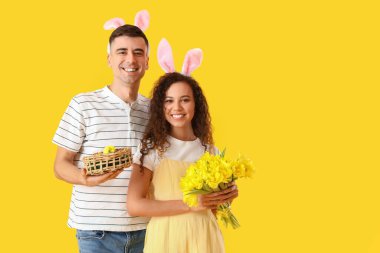 Sarı arka planda Paskalya yumurtaları ve laleleri olan mutlu çift.