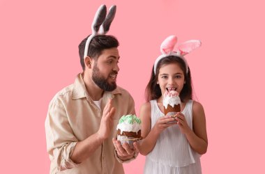 Babasıyla küçük bir kız ve pembe arka planda paskalya pastaları.