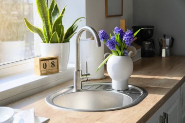 Lavabolu mutfak tezgahı, güzel çiçekler ve 8 Mart tarihli küp takvimi. Uluslararası Kadınlar Günü kutlamaları