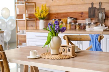 8 Mart tarihli küp takvimi, mutfaktaki yemek masasında çiçekler ve bir fincan kahve. Uluslararası Kadınlar Günü kutlamaları