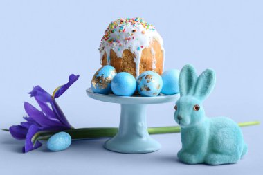 Tatlı Paskalya tavşanı, gri arka planda boyalı yumurta ve pastayla tatlı standı.