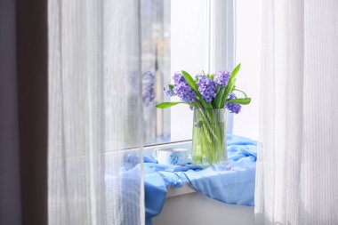 Vazo, sümbül çiçekleri ve pencere kenarında bir fincan çay.