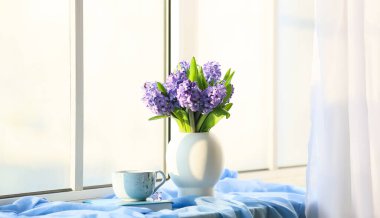 Güzel sümbül çiçekli vazo, pencere kenarında kitap ve bir fincan çay.