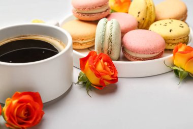 Tatlı badem kurabiyeleri, bir fincan kahve ve beyaz arka planda gül çiçekleri. Uluslararası Kadınlar Günü kutlamaları