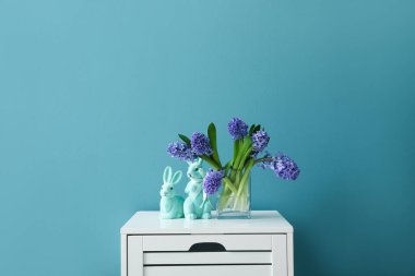 Sümbül çiçekli masa ve renkli duvarın yanında Paskalya tavşanları.