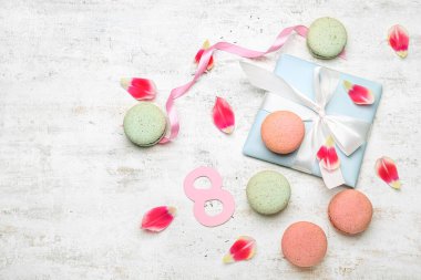 Uluslararası Kadınlar Günü kutlaması için hediye edilen kompozisyon, açık arkaplanda tatlı badem kurabiyeleri ve çiçek yaprakları