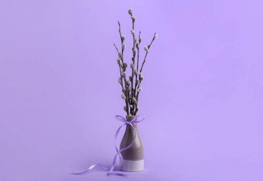Vase with pussy willow branches on lilac background