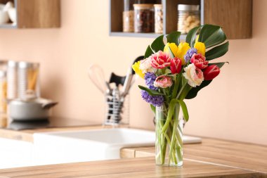 Mutfak tezgahındaki renkli duvarın yanındaki vazoda güzel bir çiçek buketi.