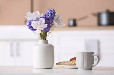 Çiçekli vazo ve masada lezzetli bir kahvaltı.