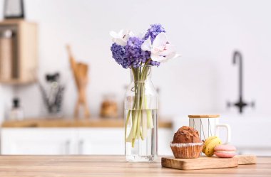 Mutfak tezgahında çiçekler olan lezzetli bir kahvaltı ve vazo.