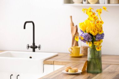 Güzel çiçekli vazo ve ahşap mutfak tezgahında makarna.