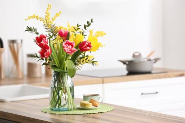 Güzel çiçekli vazo, badem kurabiyesi ve mutfak tezgahında bir fincan kahve.