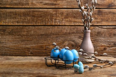 Painted Easter eggs and vase with pussy willow branches on wooden background