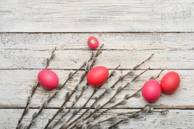 Painted Easter eggs and pussy willow branches on wooden background