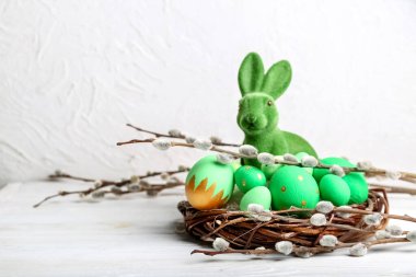 Söğüt dalları, tavşan ve yuvanın arka planında boyanmış Paskalya yumurtaları