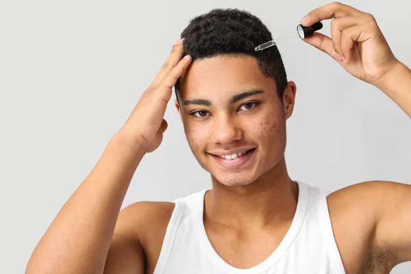 Young African American Guy Using Serum Hair Growth Grey Background — Stock Photo, Image