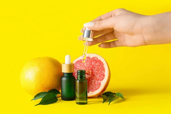 Female Hand Bottles Grapefruit Essential Oil Yellow Background Closeup — Stock Photo, Image