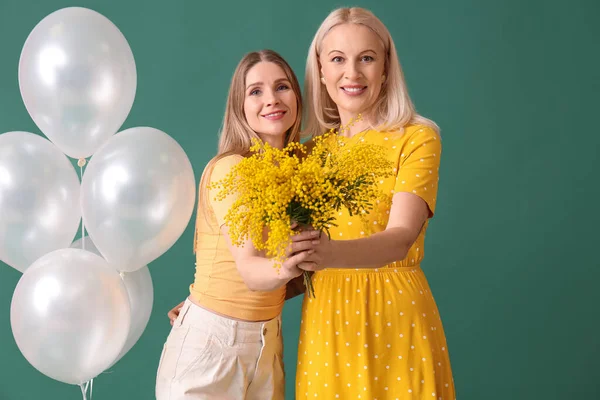 Jonge Vrouw Haar Moeder Met Bloemen Ballonnen Groene Achtergrond — Stockfoto