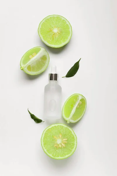 Zusammensetzung Mit Einer Flasche Ätherischem Und Geschnittenen Bergamottenfrüchten Auf Weißem — Stockfoto