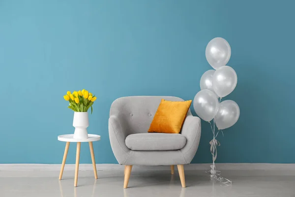 室内彩墙附近的扶手椅 桌子上的郁金香和空气气球 — 图库照片