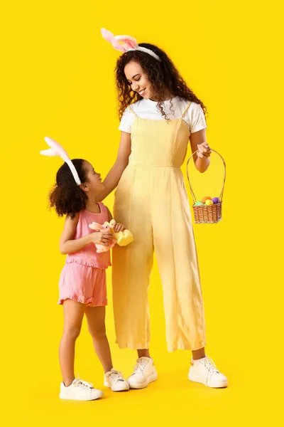 Malá Afroamerická Dívka Velikonočními Králíky Její Matka Vejce Žlutém Pozadí — Stock fotografie
