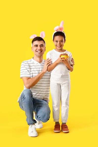 幸せな男の子と彼の父とともにイースターケーキで黄色の背景 — ストック写真