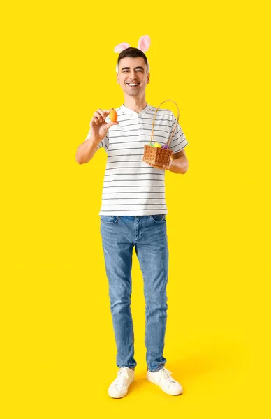 Gelukkige Jongeman Konijnenoren Houden Mand Met Paaseieren Gele Achtergrond — Stockfoto
