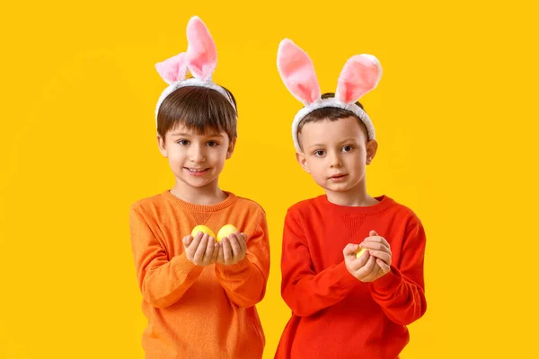Niedliche Kleine Jungen Mit Hasenohren Und Ostereiern Auf Gelbem Hintergrund — Stockfoto