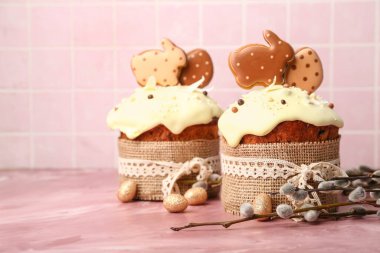 Söğüt dalları, Paskalya pastaları ve pembe arka planda boyanmış yumurtalar.