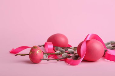 Söğüt dalları, kurdele ve pembe arka planda Paskalya yumurtaları.