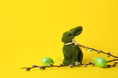 Söğüt dalları, tavşan ve sarı arka planda boyanmış Paskalya yumurtaları.