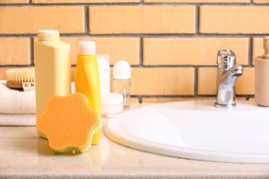 Banyo süngeri ve kozmetik ürünleri lavabonun yanındaki masada.