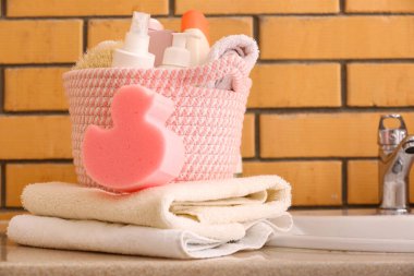 Temiz havlular, sünger ve sepet, banyo malzemeleri lavabonun yanında.