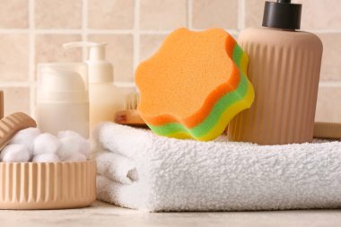 Renkli fayansların yanındaki masada farklı banyo aksesuarları ve kozmetik ürünleri var.