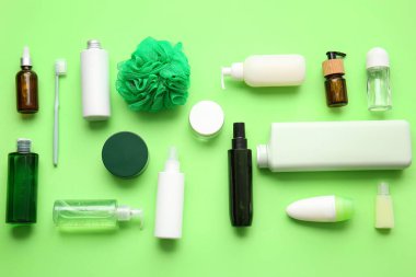Yeşil arka planda farklı kozmetik ürünleri, diş fırçası ve banyo süngeri.