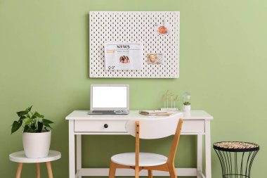 Yeşil duvarda farklı malzemeler ve tahta olan modern işyeri.