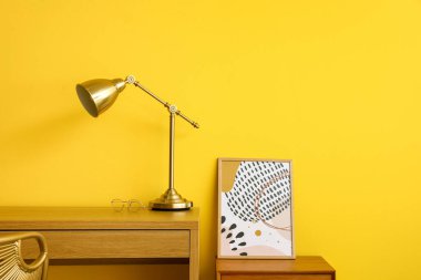 Sarı duvarın yanında altın lambalı ahşap masa.