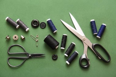 Yeşil arkaplan üzerinde makas ve düğme ile iplik makaraları