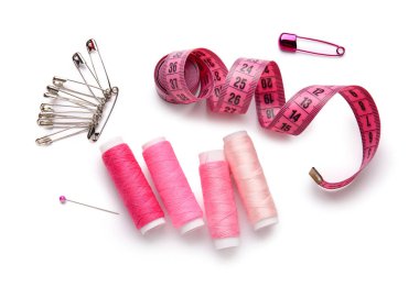 Ölçüm bandı ve beyaz arkaplan üzerindeki iğnelerle iplik makaraları