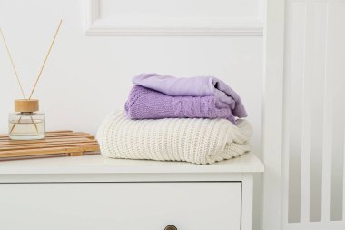 Açık duvarın yanındaki çekmecelerin üzerine örülmüş süveterler.